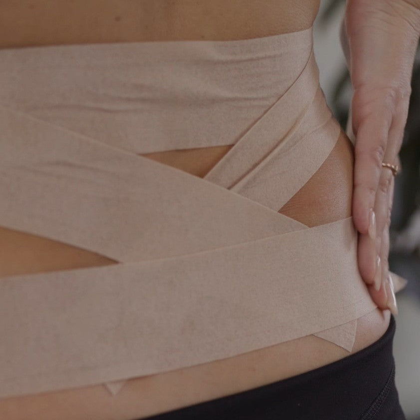 Applying McConnell Under Tape Sensitive to the lower back for skin protection and comfort during McConnell taping