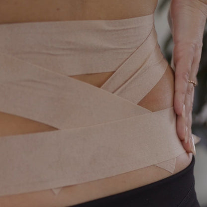 Applying McConnell Under Tape Sensitive to the lower back for skin protection and comfort during McConnell taping